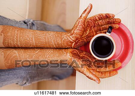 Close-up of a woman's henna tattooed hands holding a cup of tea View Large Photo Image Stock Image - Close-up of a woman's henna tattooed hands holding a cup of tea. Fotosearch
