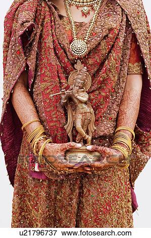 Mid section view of a bride holding an idol of lord Krishna View Large Photo Image Stock Photo - Mid section view of a bride holding an idol of lord Krishna. Fotosearch
