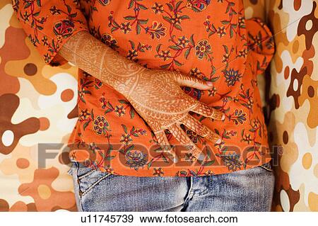 Mid section view of a woman with her henna tattooed hand on her abdomen View Large Photo Image Stock Photo - Mid section view of a woman with her henna tattooed hand on her abdomen. Fotosearch