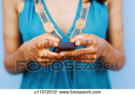 Mid section view of a young woman holding a mobile phone View Large Photo Image Stock Photo - Mid section view of a young woman holding a mobile phone. Fotosearch