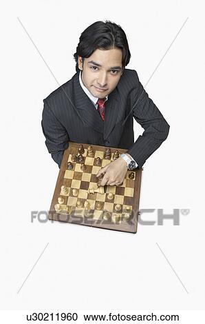 Stock Image - High angle view of a businessman holding a chessboard. Fotosearch