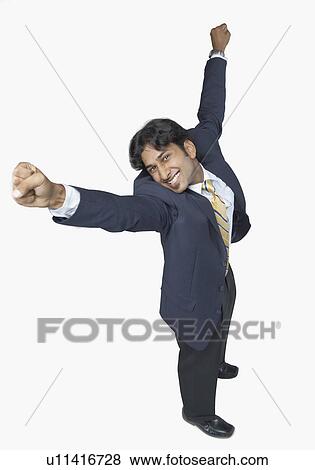 Stock Photo - High angle view of a businessman standing with his arms raised and smiling. Fotosearch