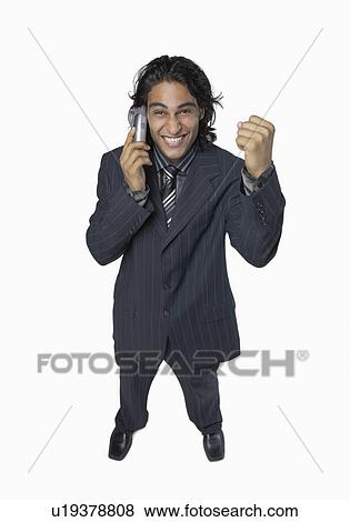 Stock Photo - High angle view of a businessman talking on a mobile phone and clenching his fist. Fotosearch