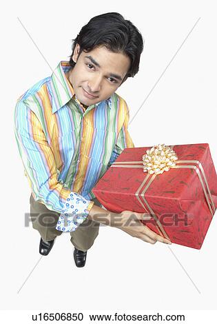 Stock Image - High angle view of a young man holding a gift. Fotosearch
