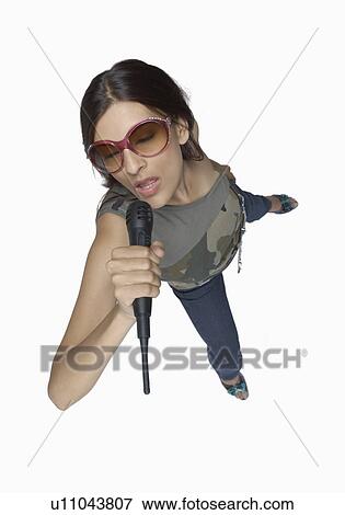 Stock Photo - High angle view of a young woman singing into a microphone. Fotosearch