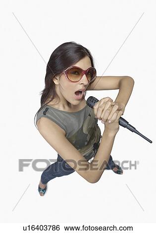 High angle view of a young woman singing into a microphone View Large Photo Image Stock Photograph - High angle view of a young woman singing into a microphone. Fotosearch