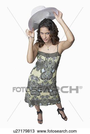 Stock Image - Portrait of a young woman holding a hat over her head. Fotosearch