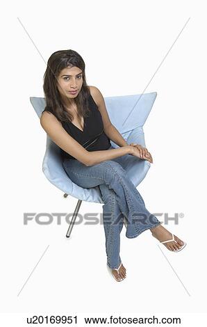 Portrait of a young woman sitting on a chair View Large Photo Image Stock Image - Portrait of a young woman sitting on a chair. Fotosearch