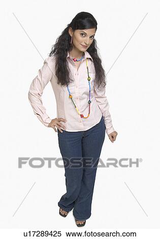 Portrait of a young woman standing with her hand on hip View Large Photo Image Stock Photography - Portrait of a young woman standing with her hand on hip. Fotosearch