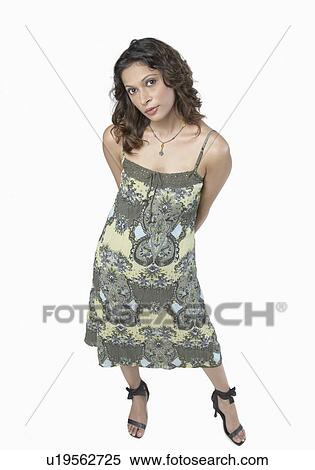 Portrait of a young woman standing with her hands behind her back View Large Photo Image Stock Photography - Portrait of a young woman standing with her hands behind her back. Fotosearch