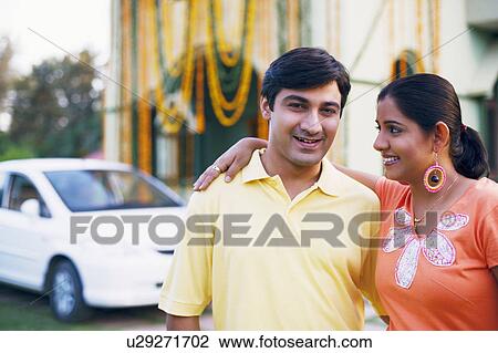 Stock Image - Close-up of a young couple standing in front of a decorated house and smiling. Fotosearch