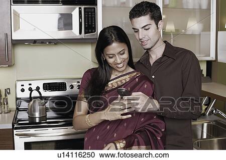 Stock Image - Close-up of a young man showing a young woman a mobile phone. Fotosearch