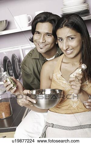 Picture - Portrait of a young couple holding herbs in two small jars. Fotosearch
