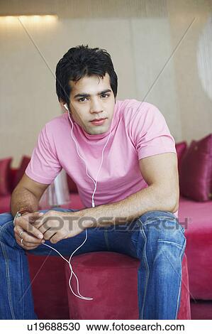 Stock Image - Portrait of a young man wearing headphones and listening to music. Fotosearch