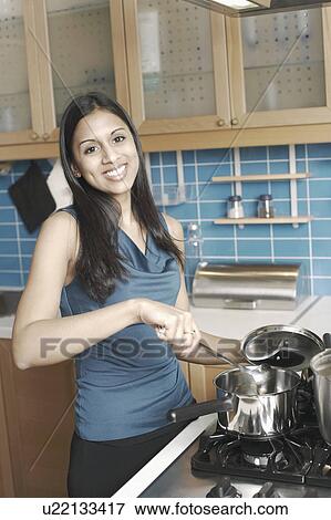 Portrait of a young woman cooking in the kitchen View Large Photo Image Stock Photo - Portrait of a young woman cooking in the kitchen. Fotosearch