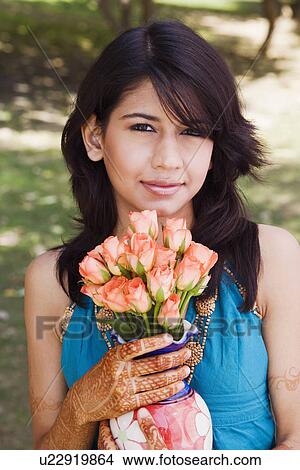 Picture - Portrait of a young woman holding a vase of Roses. Fotosearch