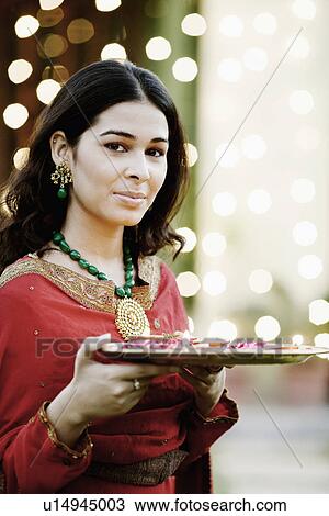 Stock Image - Portrait of a young woman holding oil lamps and Rose petals in a plate. Fotosearch