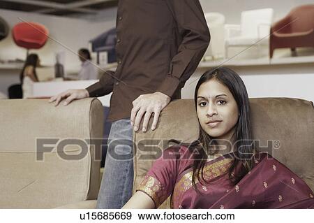 Stock Photo - Portrait of a young woman sitting in a furniture store. Fotosearch