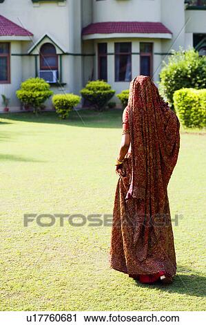 Rear view of a bride in traditional wedding dress walking in a lawn View Large Photo Image Stock Image - Rear view of a bride in traditional wedding dress walking in a lawn. Fotosearch