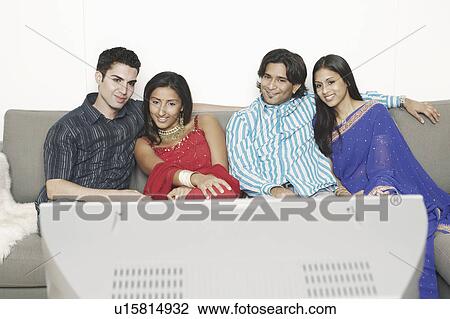 Stock Image - Two young couples sitting on a couch and watching television. Fotosearch