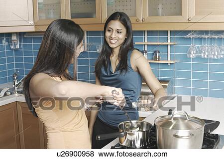 Stock Photo - Two young women cooking in the kitchen. Fotosearch