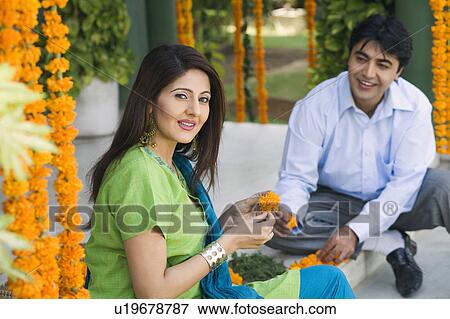 Stock Photo - Young couple sitting and decorating doorstep of a house. Fotosearch