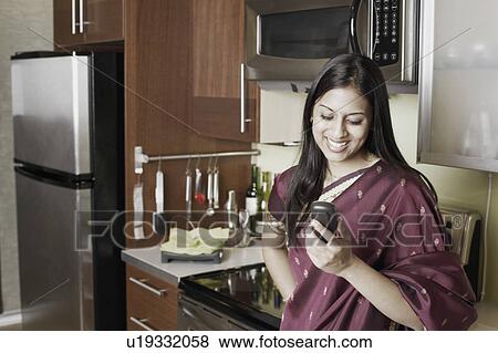 Stock Photo - Young woman holding a mobile phone. Fotosearch