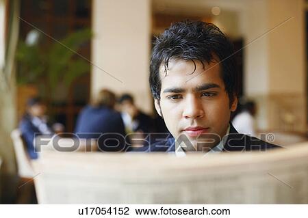 Stock Image - Close-up of a businessman reading a newspaper. Fotosearch