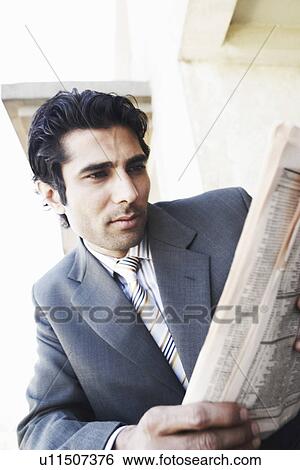 Stock Photograph - Close-up of a young man reading a newspaper. Fotosearch