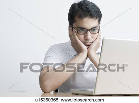 Close-up of a young man sitting in front of a laptop with his head in his hands View Large Photo Image Stock Photography - Close-up of a young man sitting in front of a laptop with his head in his hands. Fotosearch