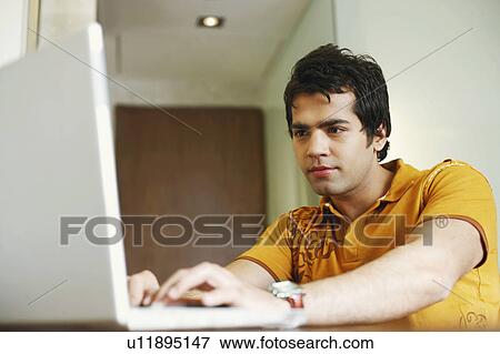 Close-up of a young man working on a laptop View Large Photo Image Stock Photo - Close-up of a young man working on a laptop. Fotosearch