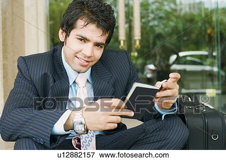 Stock Photo - Portrait of a businessman holding a passport and smiling. Fotosearch