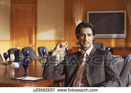 Portrait of a businessman sitting in a conference room and smiling View Large Photo Image Stock Photo - Portrait of a businessman sitting in a conference room and smiling. Fotosearch
