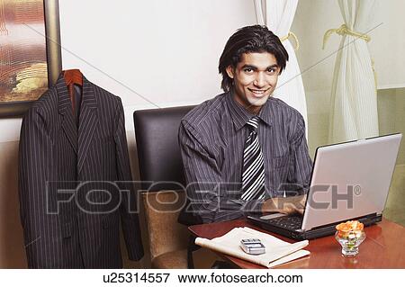 Stock Photo - Portrait of a businessman sitting in an office and using a laptop. Fotosearch