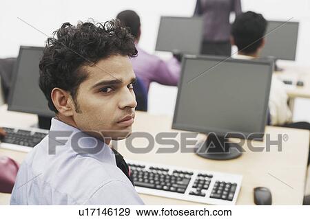 Portrait of a businessman sitting in front of a computer View Large Photo Image Stock Photo - Portrait of a businessman sitting in front of a computer. Fotosearch