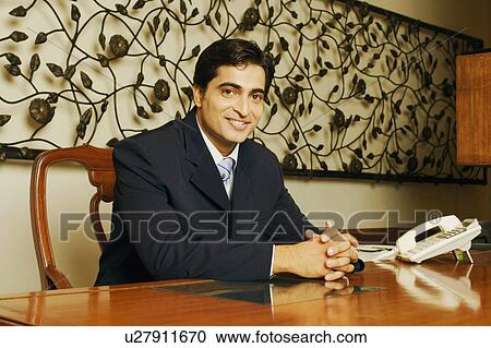 Stock Image - Portrait of a businessman smiling with his hands clasped. Fotosearch