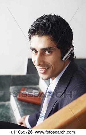 Stock Photograph - Portrait of a businessman wearing a hands free device and smiling. Fotosearch
