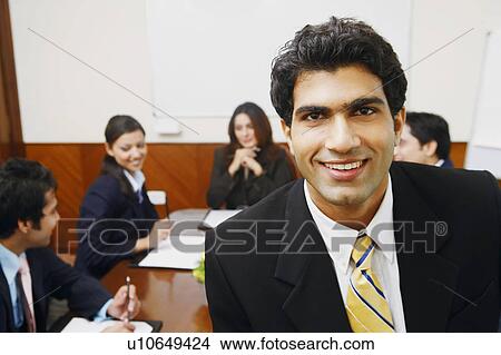 Picture - Portrait of a businessman with his colleagues sitting behind him. Fotosearch