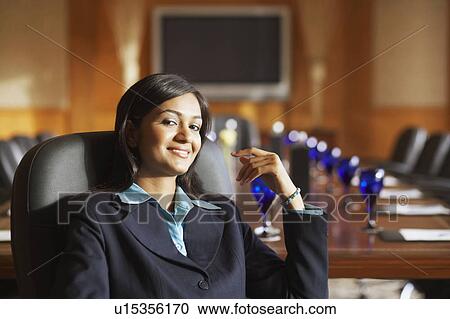 Stock Image - Portrait of a businesswoman sitting in a conference room and smiling. Fotosearch