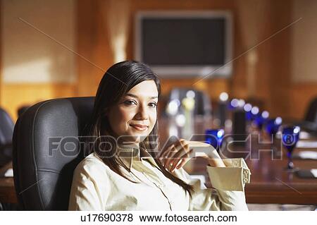Stock Photo - Portrait of a businesswoman sitting in a conference room and smiling. Fotosearch