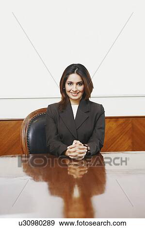 Stock Photo - Portrait of a businesswoman sitting in a conference room with her hands clasped. Fotosearch