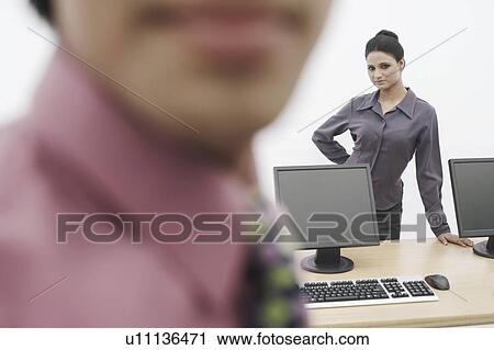 Stock Image - Portrait of a businesswoman standing behind two computers. Fotosearch