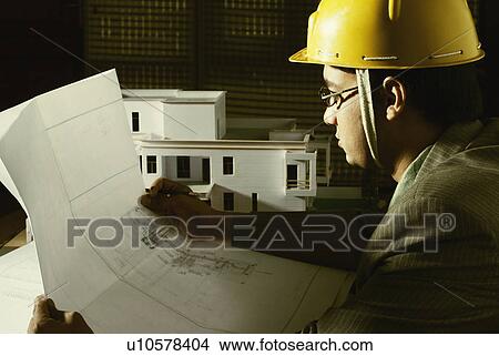 Picture - Side profile of an architect examining a blueprint. Fotosearch