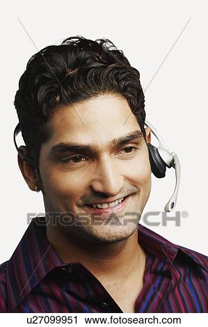 Close-up of a young man wearing a headset View Large Photo Image Stock Image - Close-up of a young man wearing a headset. Fotosearch