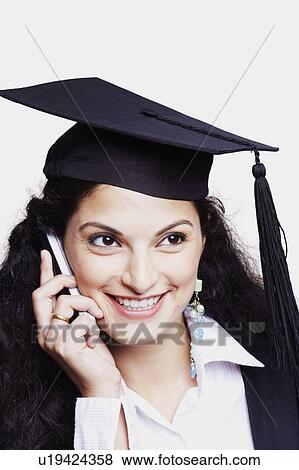 Stock Photo - Close-up of a female graduate using a mobile phone and smiling. Fotosearch