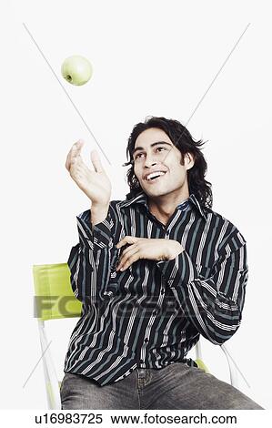Stock Photography - Close-up of a young man tossing an apple in the air. Fotosearch
