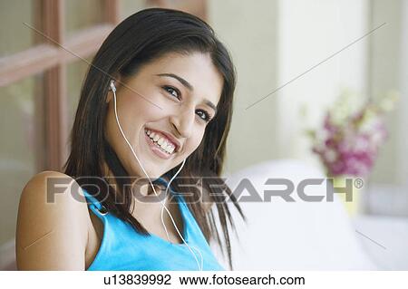 Stock Image - Close-up of a young woman wearing headphones and smiling. Fotosearch