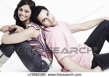 Portrait of a young couple sitting back to back on the floor and smiling View Large Photo Image Stock Image - Portrait of a young couple sitting back to back on the floor and smiling. Fotosearch