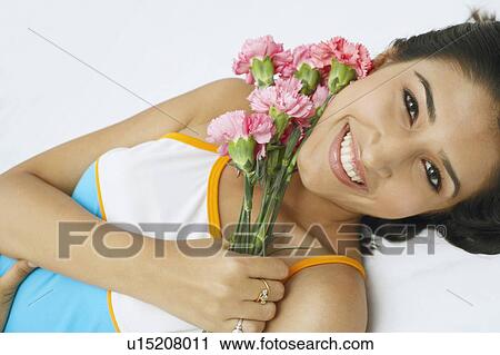 Portrait of a young woman holding a bunch of flowers and smiling View Large Photo Image Stock Image - Portrait of a young woman holding a bunch of flowers and smiling. Fotosearch