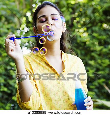 Close-up of a young woman blowing bubbles View Large Photo Image Stock Photo - Close-up of a young woman blowing bubbles. Fotosearch